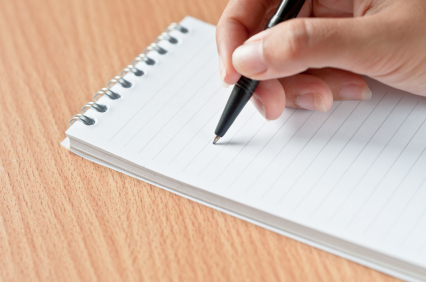 A photo showing a hand holding a pen and a paper